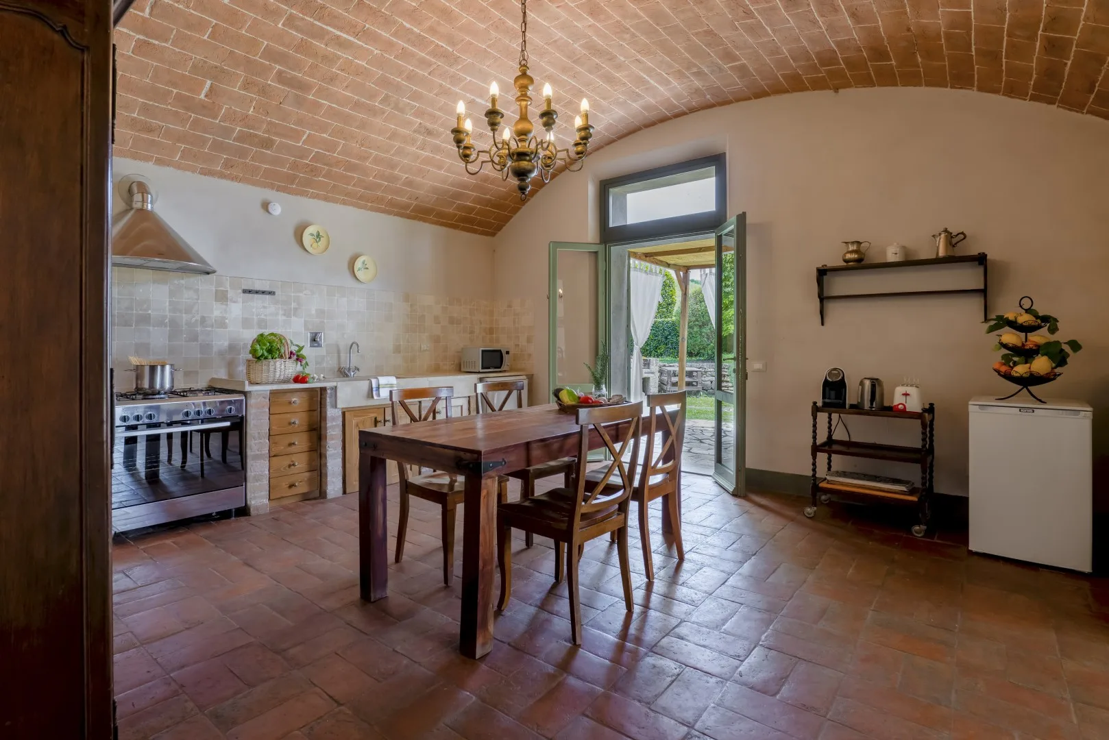 Una cocina y comedor con una mesa de madera junto a una puerta abierta.