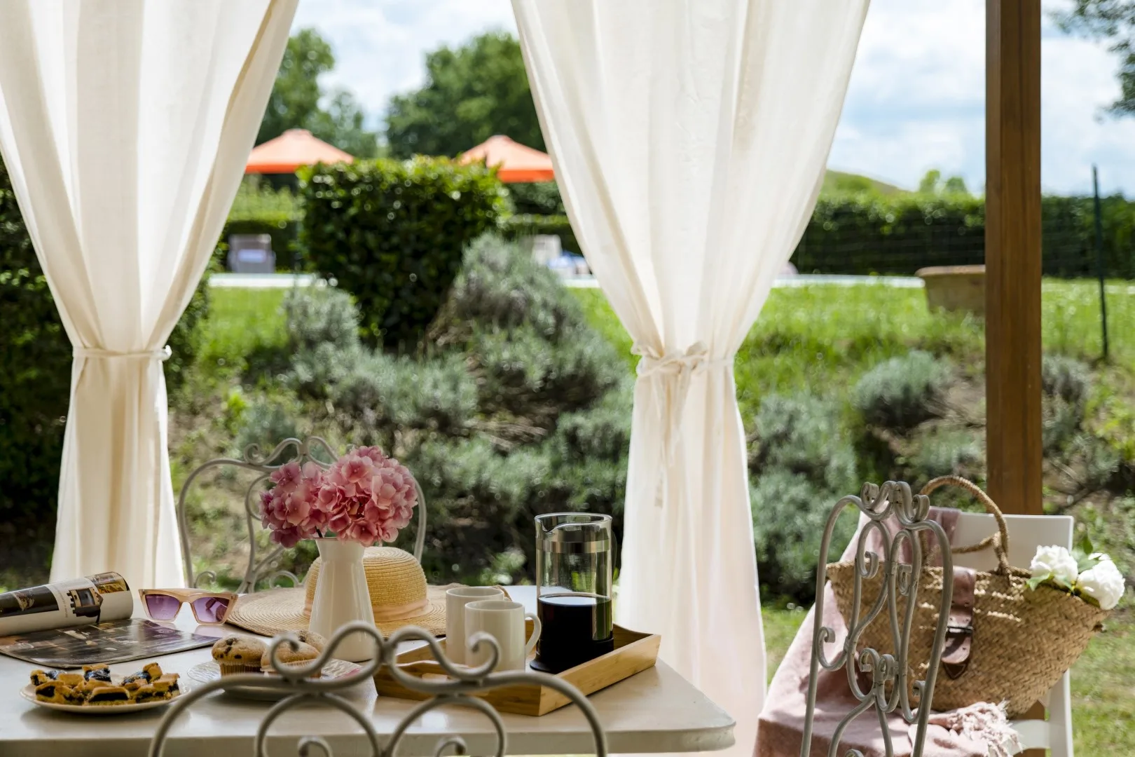 Una mesa junto a cortinas abiertas tiene vistas a un jardín frondoso.