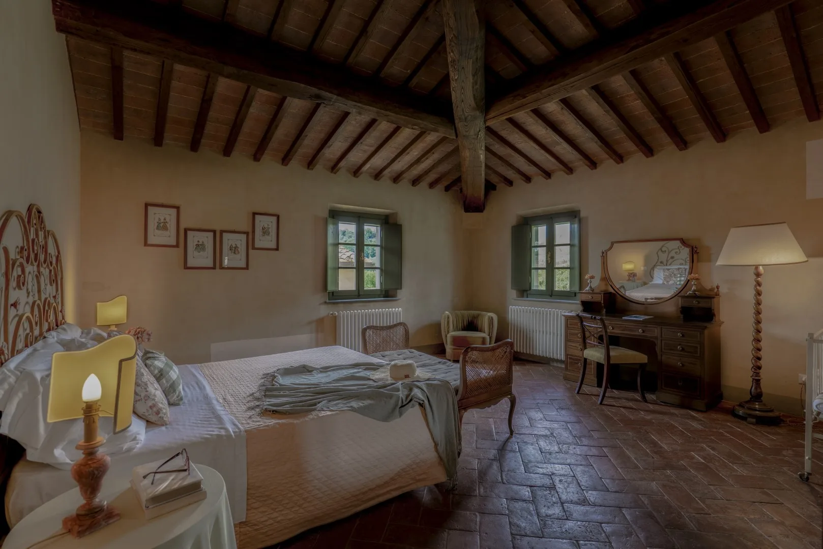 Un dormitorio con camas, ventanas y un escritorio bajo vigas expuestas.