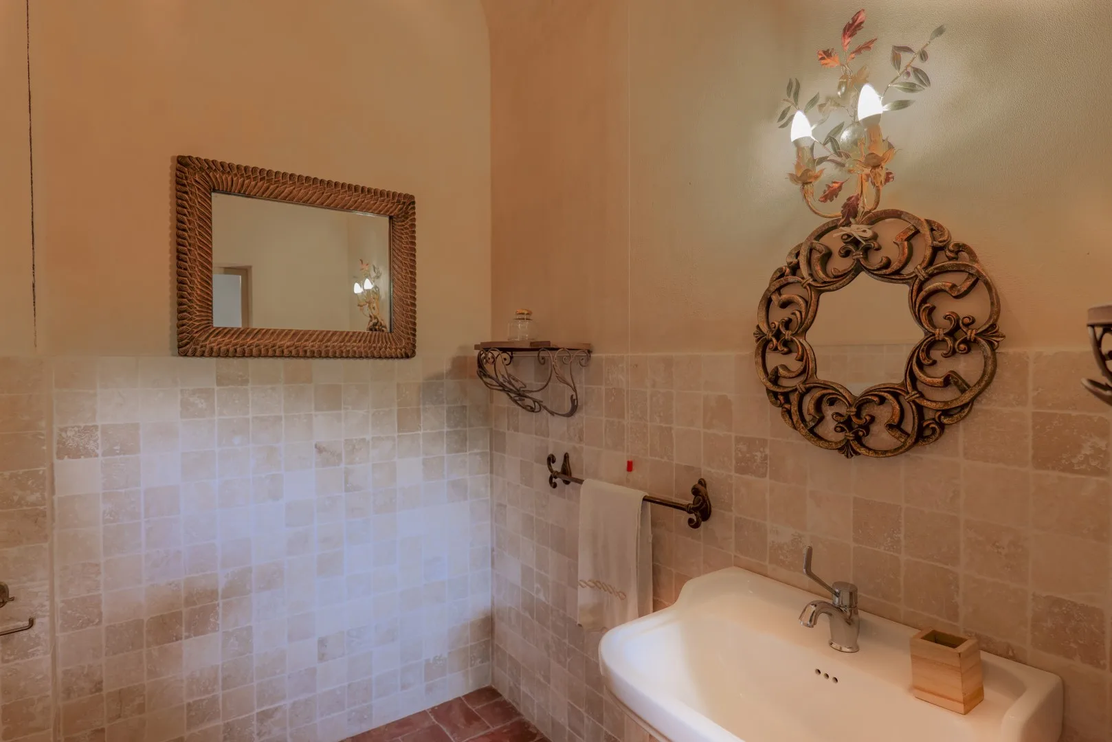 Un baño con pared de azulejos, lavabo y espejos decorativos.