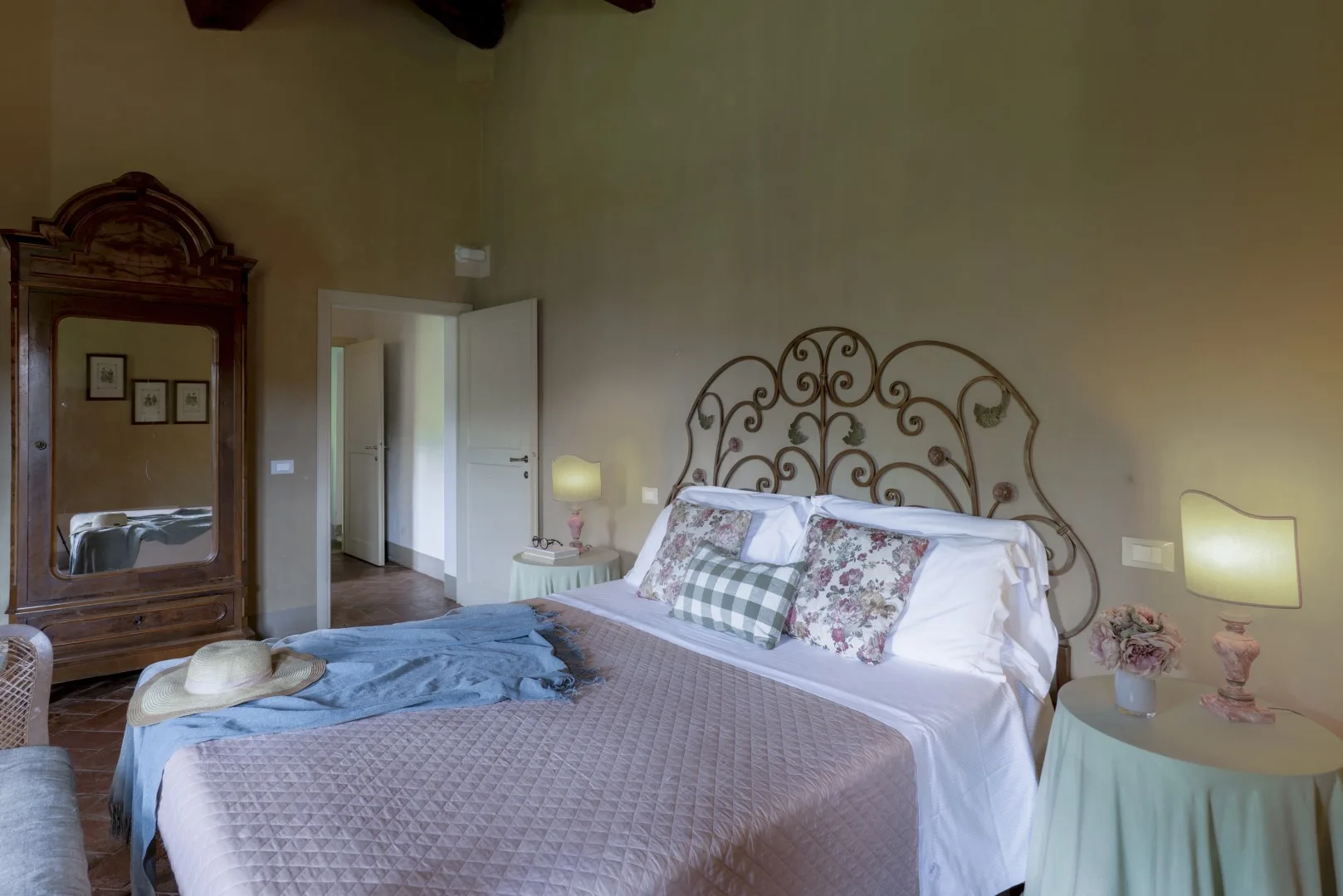 Un dormitorio con una colcha estampada y un cabecero de metal ornamentado.
