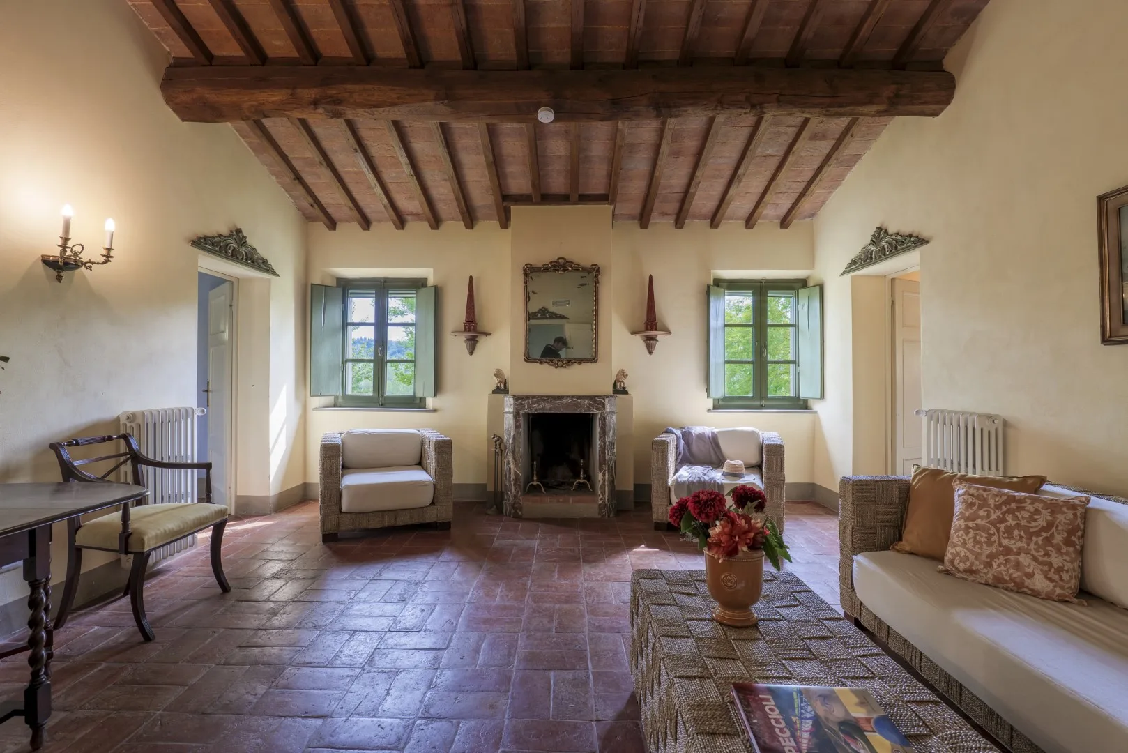 Una sala de estar con asientos alrededor de una chimenea bajo vigas de madera vistas.