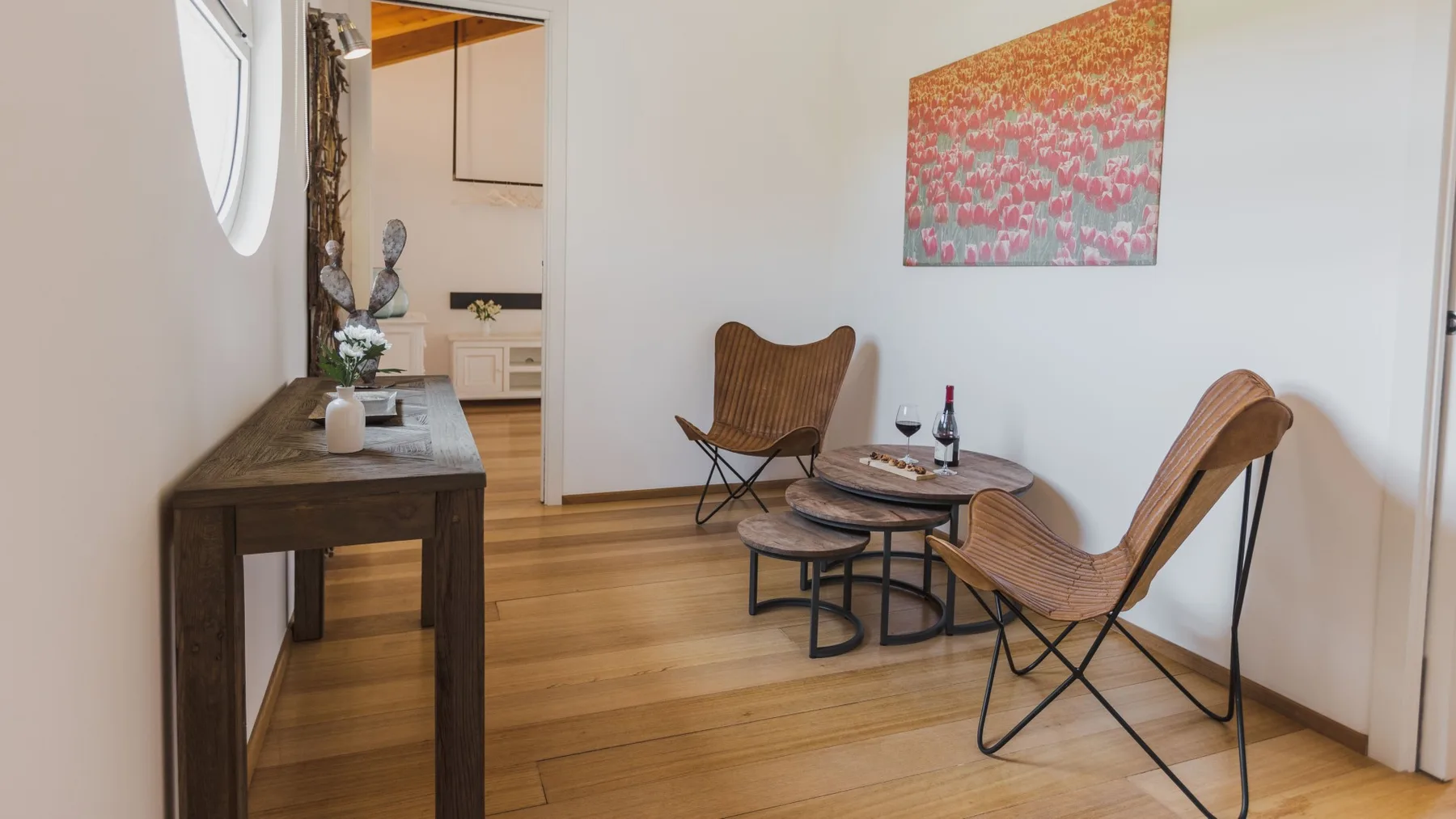 Una sala luminosa con una mesa de madera, asientos bajos y arte colorido en la pared.