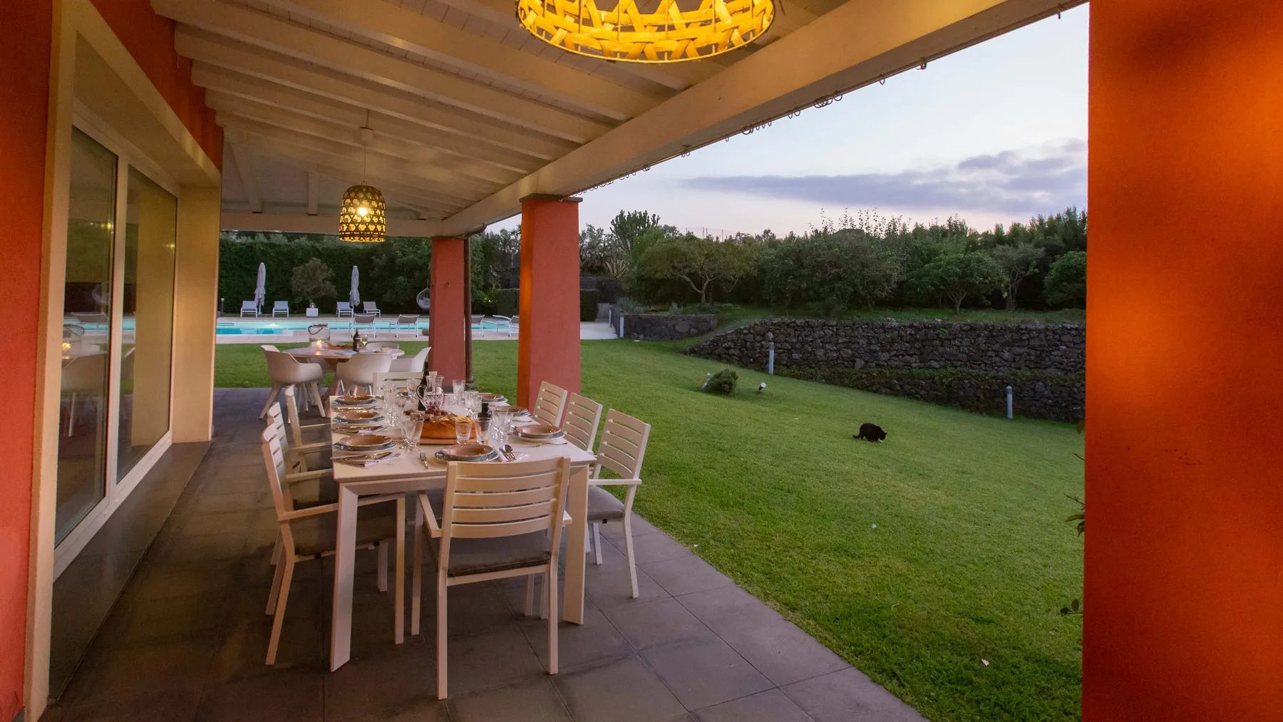Una zona de comedor cubierta da a un césped y una piscina.