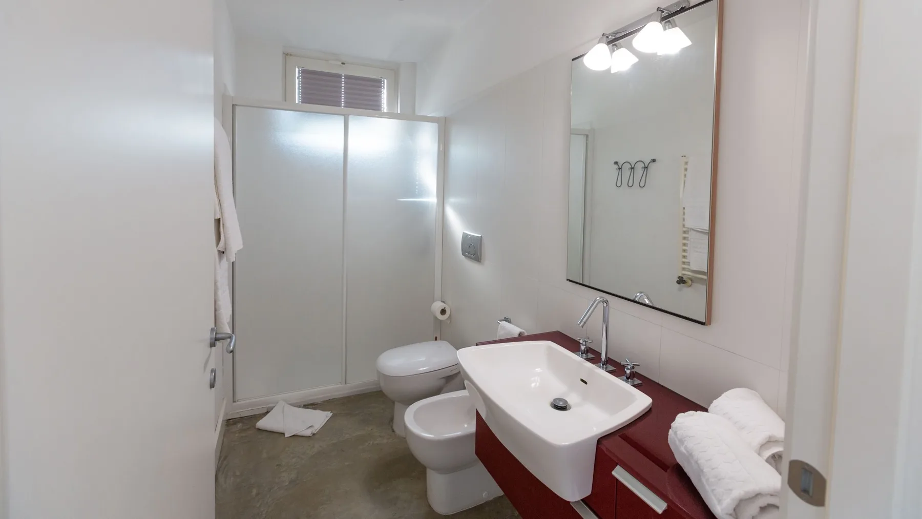 Un baño con lavabo, inodoro y una ducha con paneles de vidrio esmerilado.