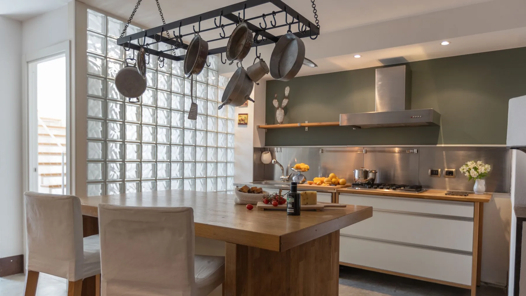 Una cocina moderna con una gran isla y utensilios de cocina colgantes.