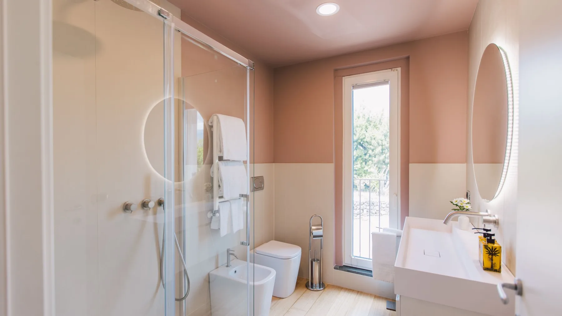 Un baño con ducha de vidrio, lavabo y una ventana alta.