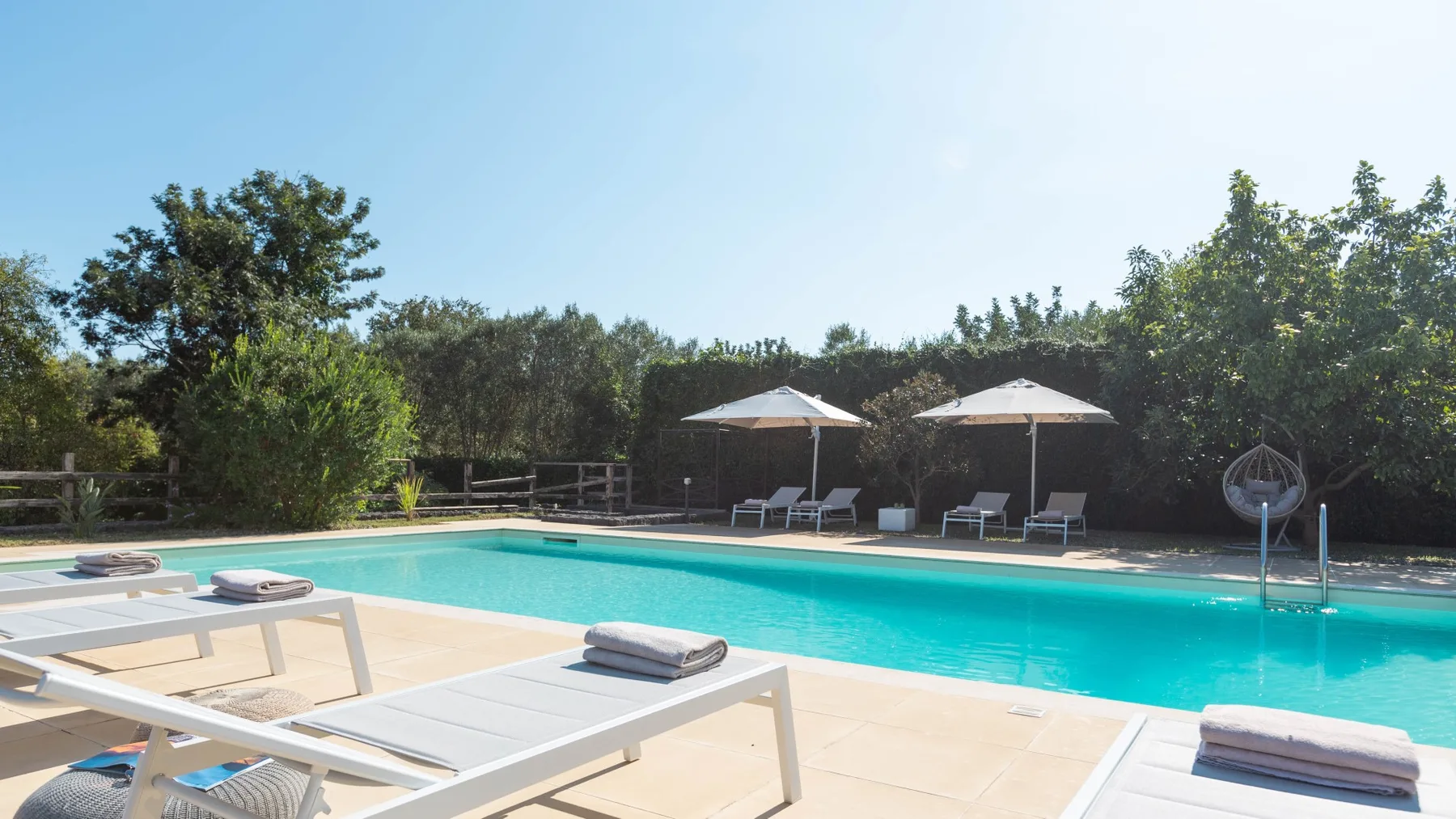 Una piscina al aire libre con tumbonas y sombrillas junto al agua.