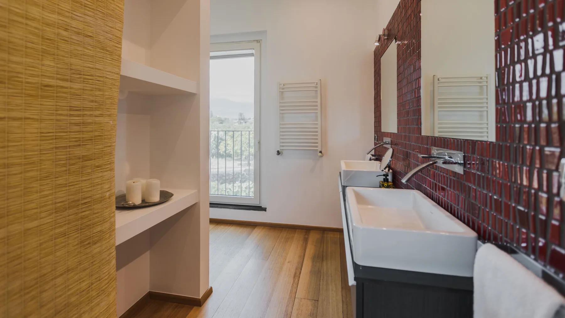Un baño con bañera, lavabo mural y paredes de azulejos rojos.