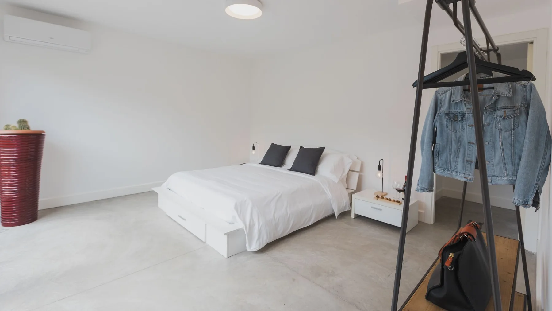 Un dormitorio luminoso con una cama bien hecha y un perchero.