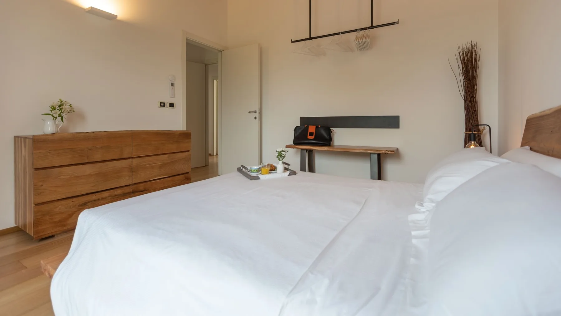 Un dormitorio con una cama bien tendida y una cómoda de madera.