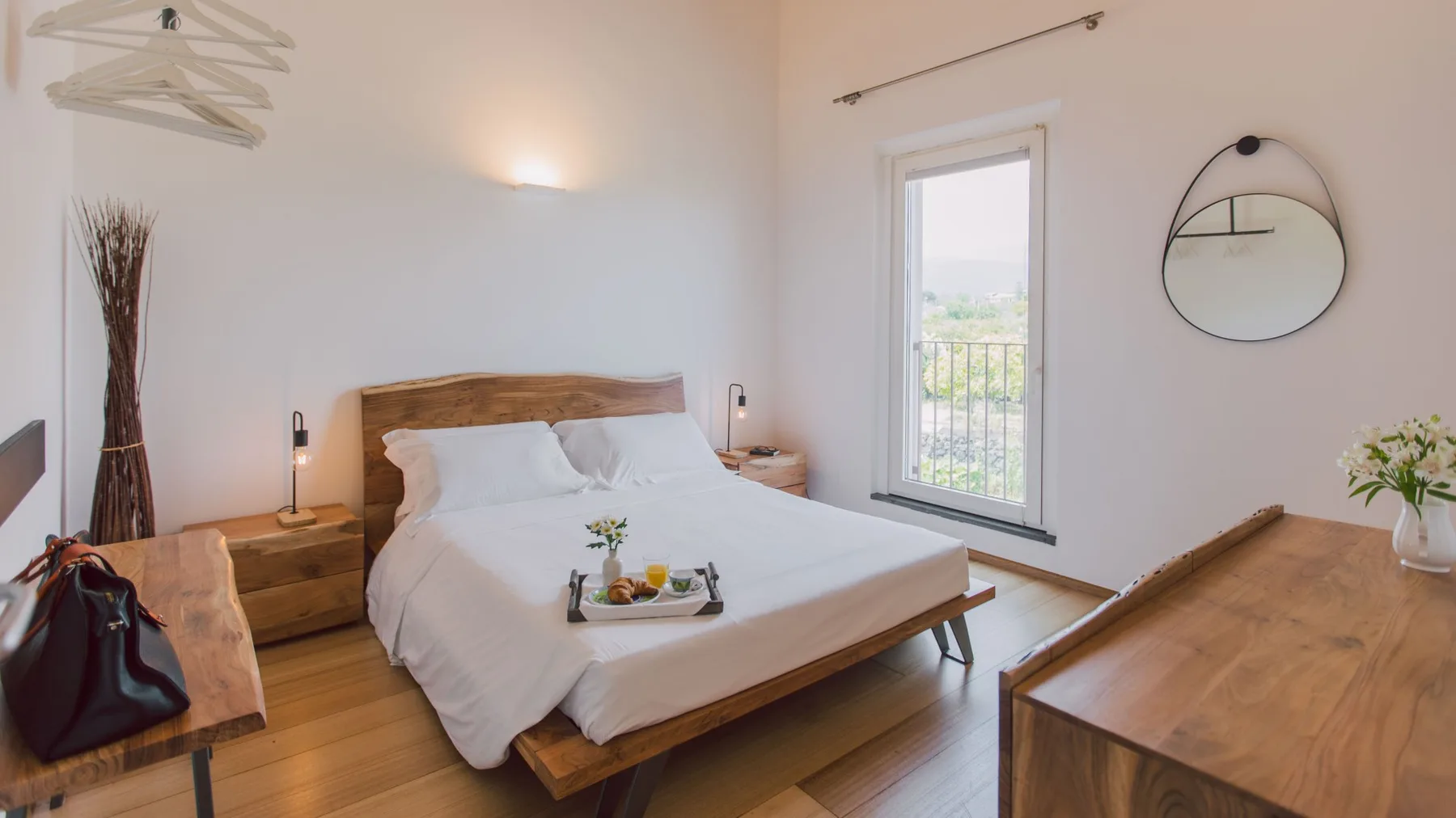 Un dormitorio luminoso con una cama, mesitas de noche y una ventana.