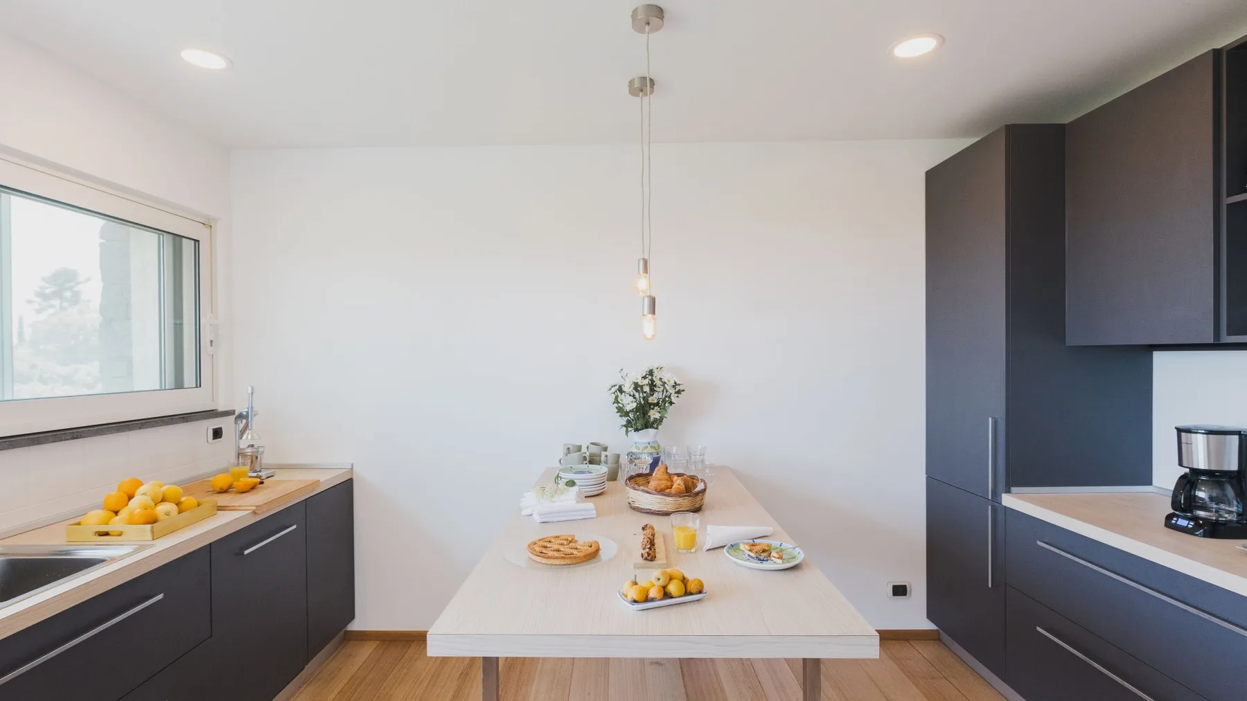 Una cocina moderna con gabinetes oscuros y una mesa puesta con comida.