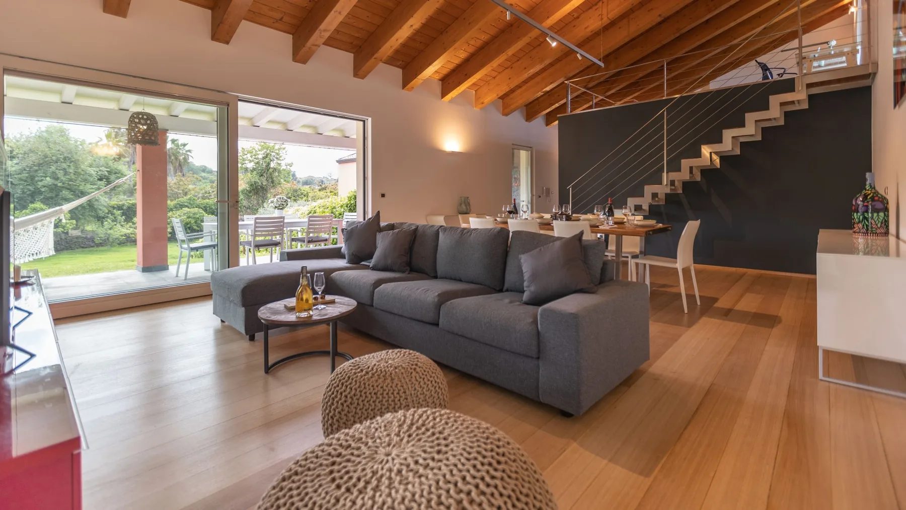 Una sala de estar con asientos grises y grandes puertas de vidrio hacia un patio.