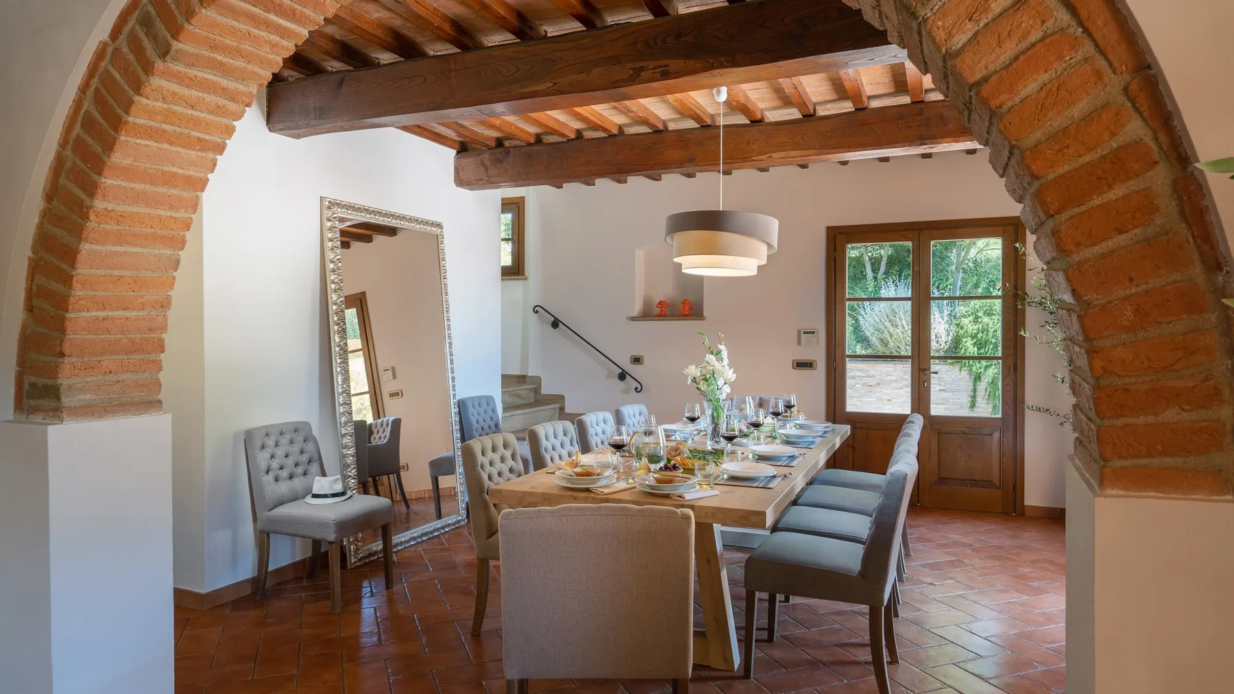 Un comedor con una mesa larga preparada bajo vigas de madera vistas.