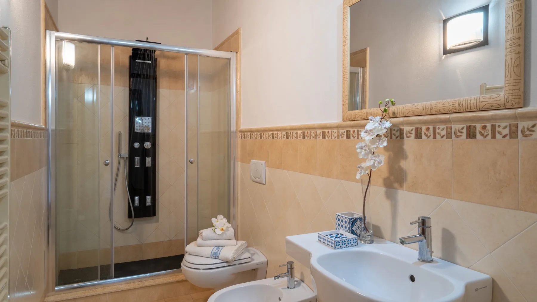 Un baño alicatado con ducha de vidrio, lavabo e inodoro.