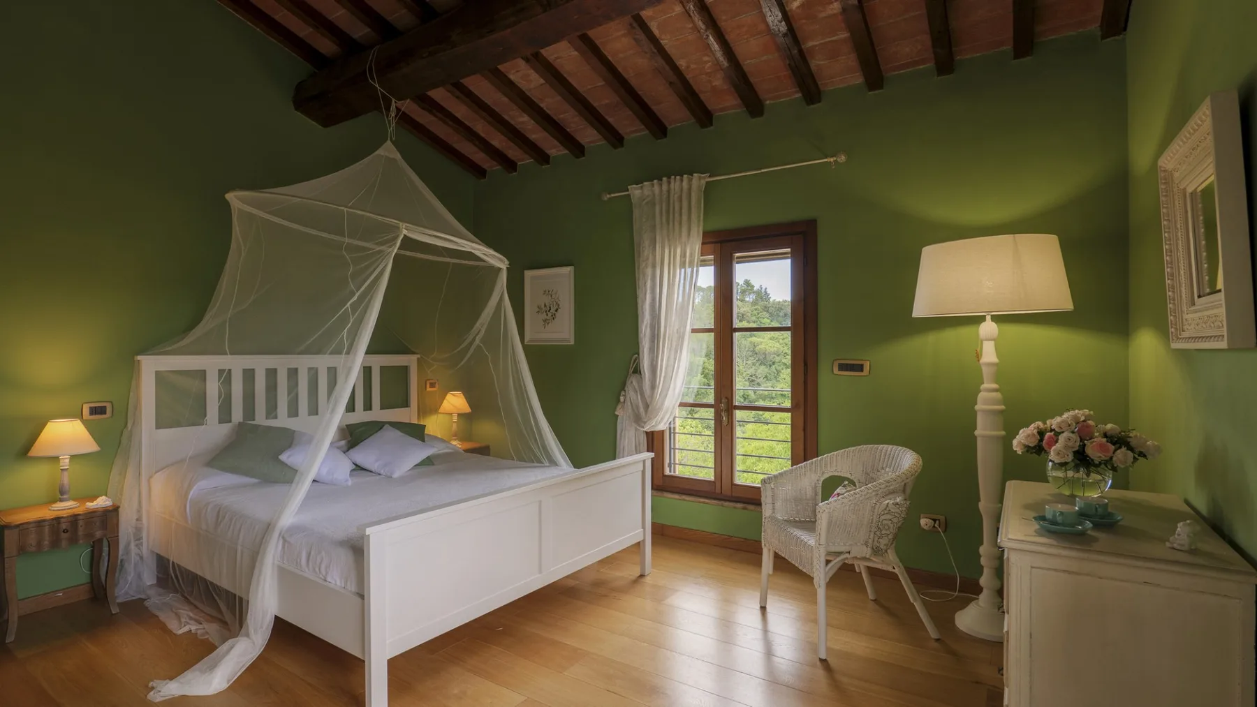 Un dormitorio con una cama blanca bajo un dosel y paredes verdes.