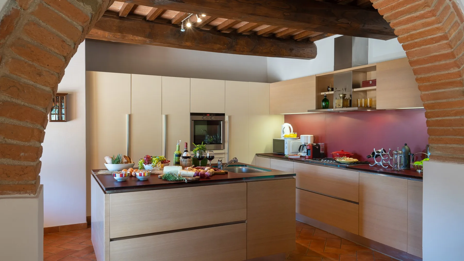 Una cocina moderna con gabinetes claros, una isla central y vigas de madera expuestas.