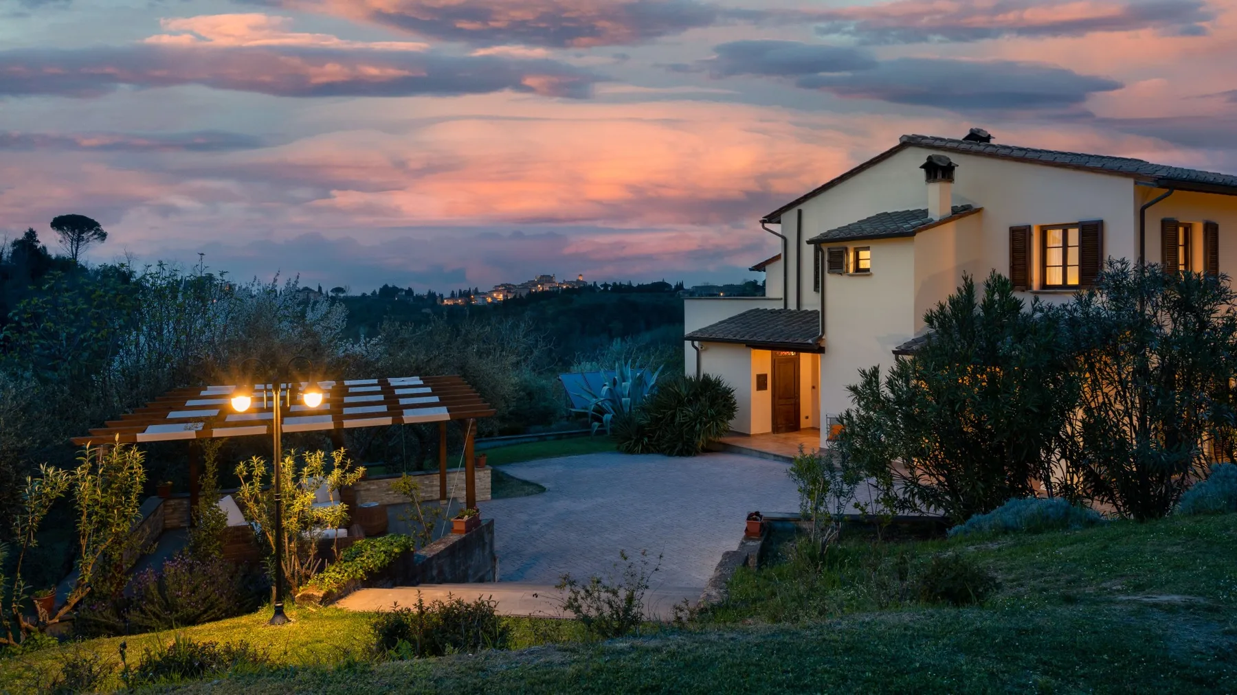 Una casa y un jardín cuidado bajo un cielo colorido al atardecer.