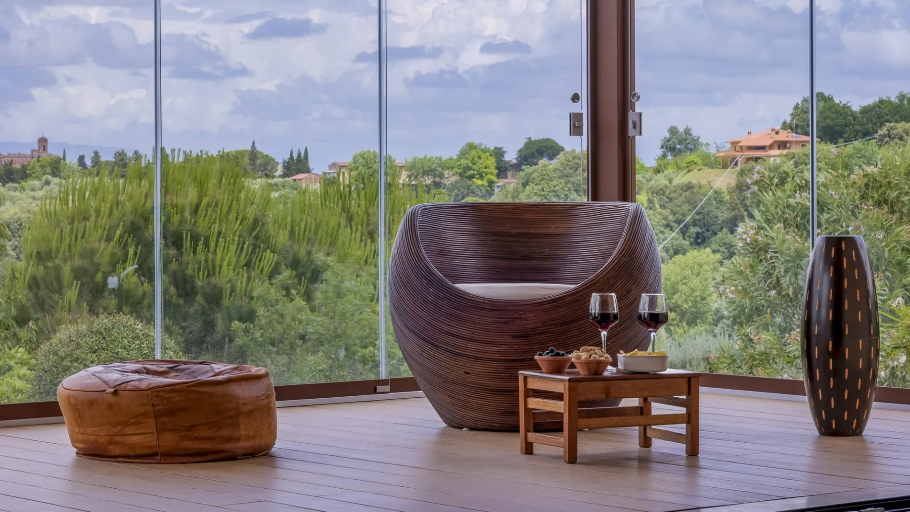 Un solárium con un asiento escultórico, una mesa baja y amplias ventanas de vidrio.