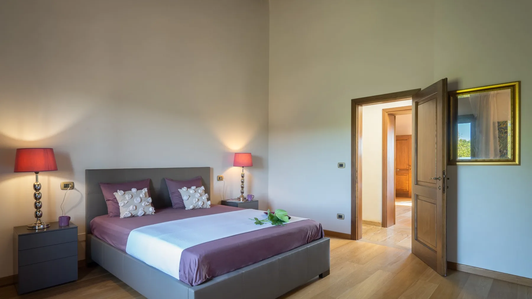Un dormitorio con una cama doble, mesillas de noche y una puerta abierta.
