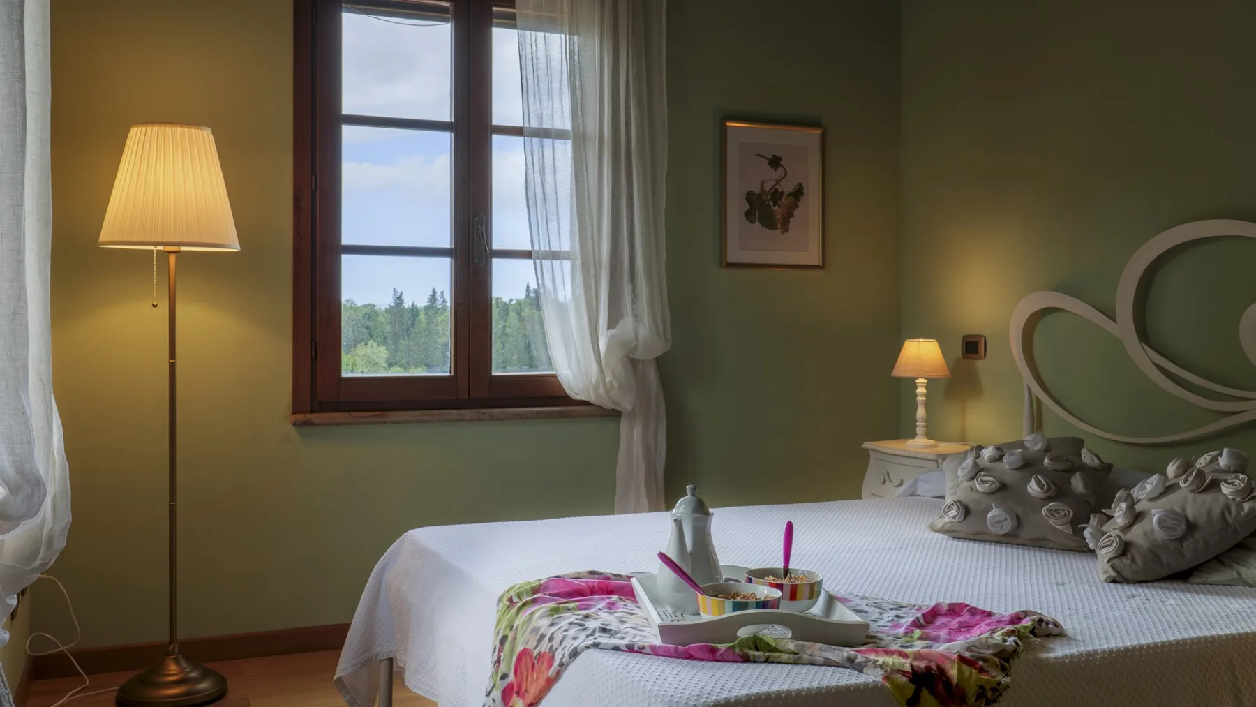 Un dormitorio con una cama tendida, una lámpara de noche y una ventana.