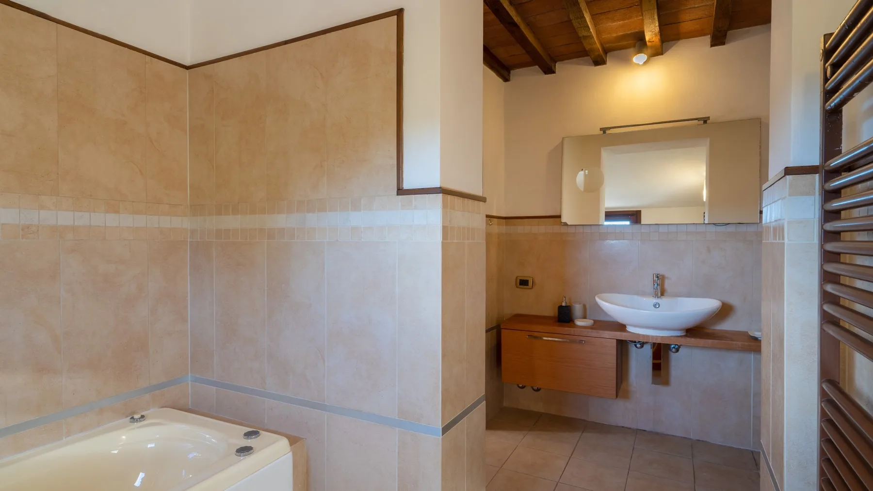Un baño revestido de azulejos con lavabo, mueble y un gran espejo.
