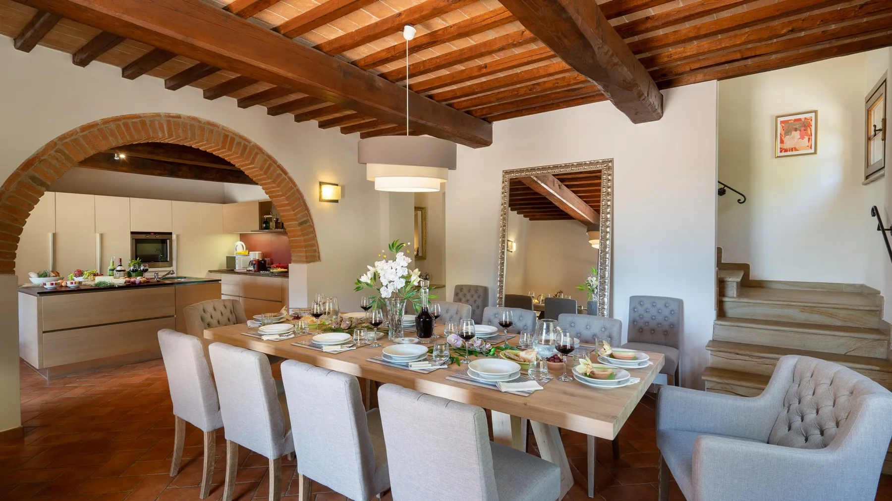 Comedor con una mesa puesta bajo vigas de madera a la vista.