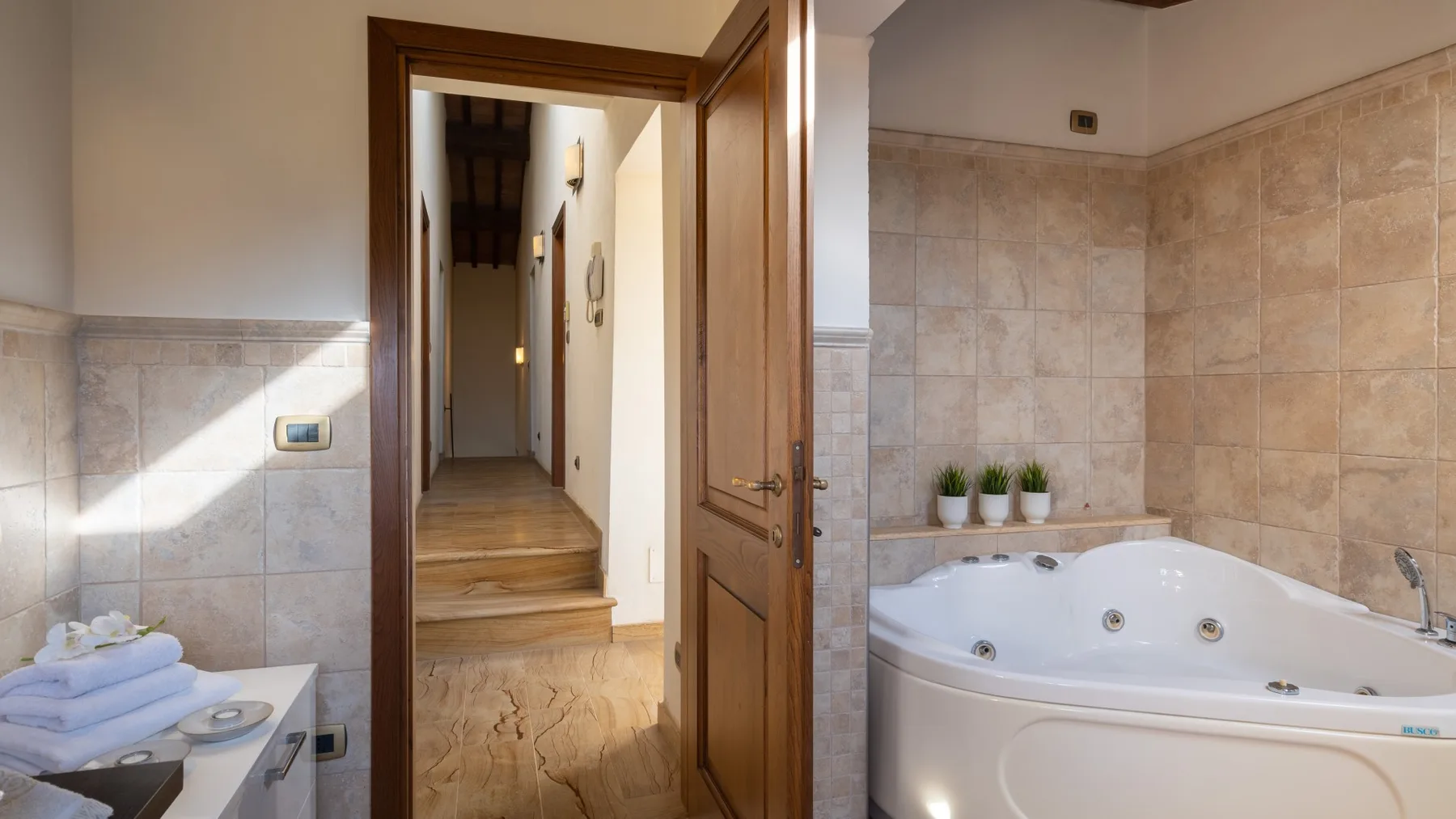 Un baño alicatado con una bañera junto a una puerta de madera abierta.