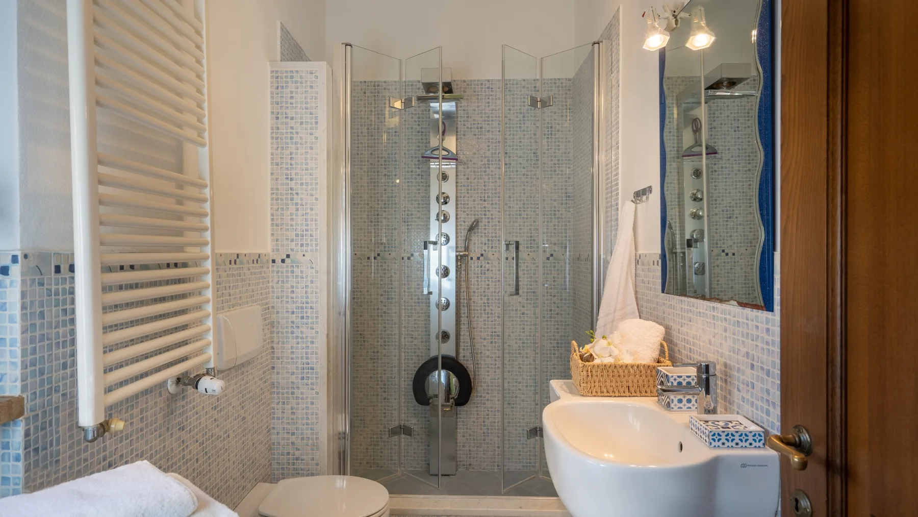 Un baño alicatado con ducha de vidrio, bañera y lavabo.