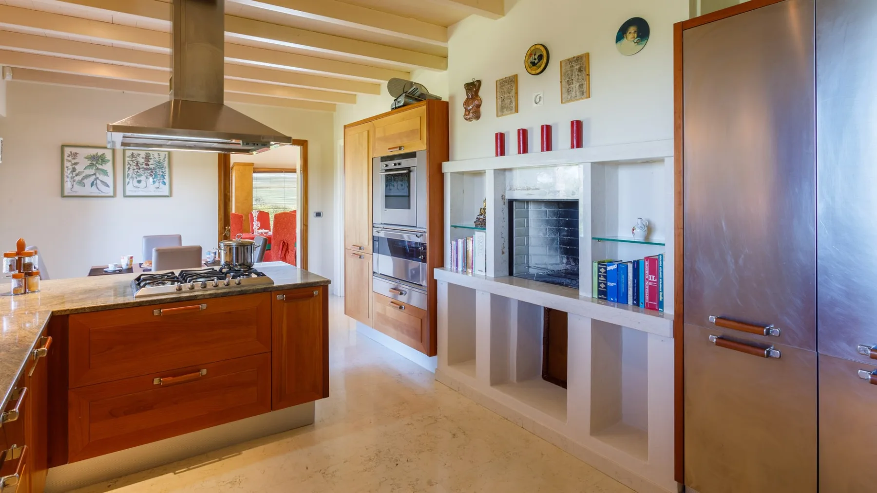 A bright kitchen features a wooden island with a cooktop, built-in ovens, and a fireplace.