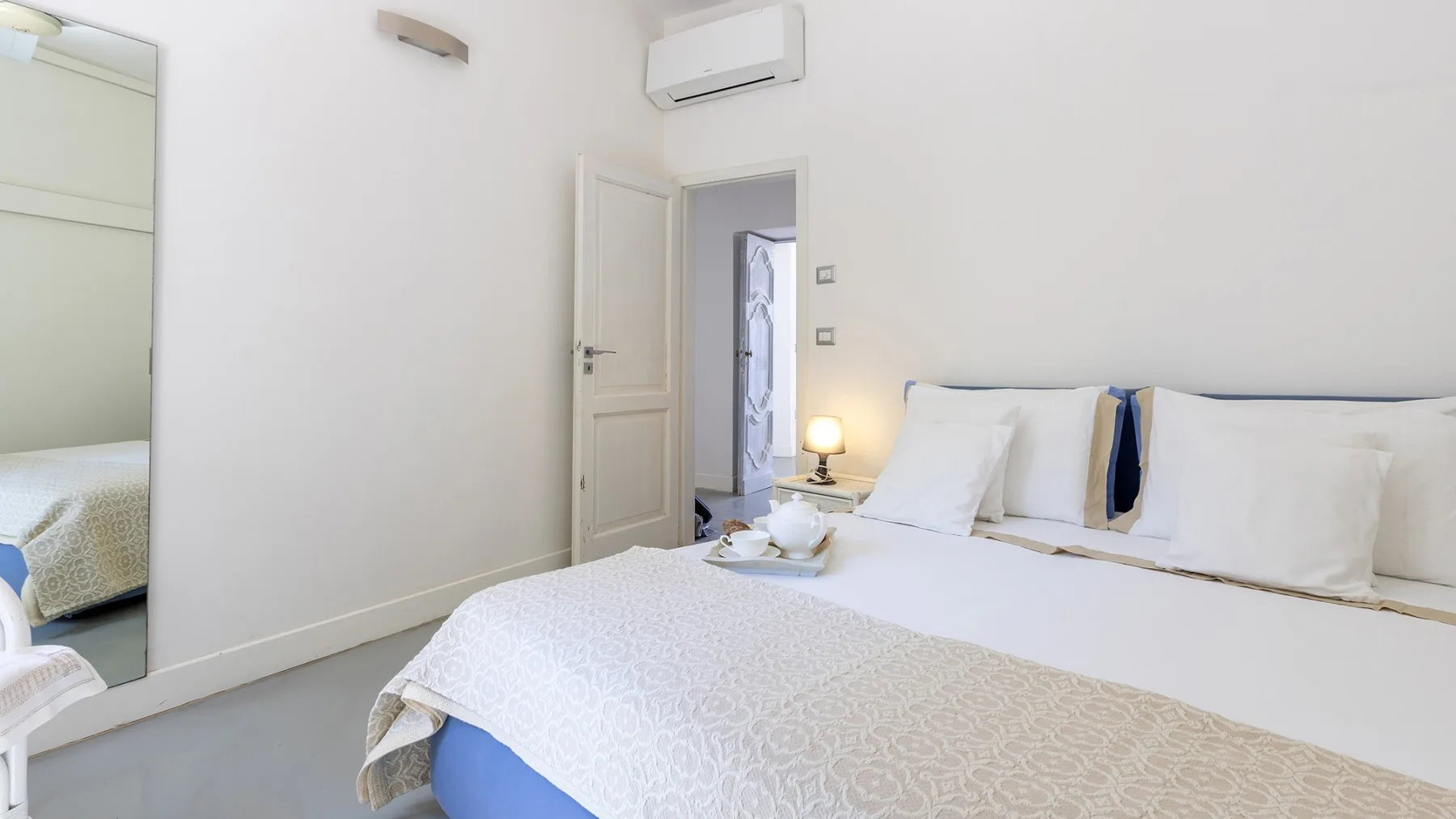 Un dormitorio luminoso con una cama bien arreglada y una puerta abierta.