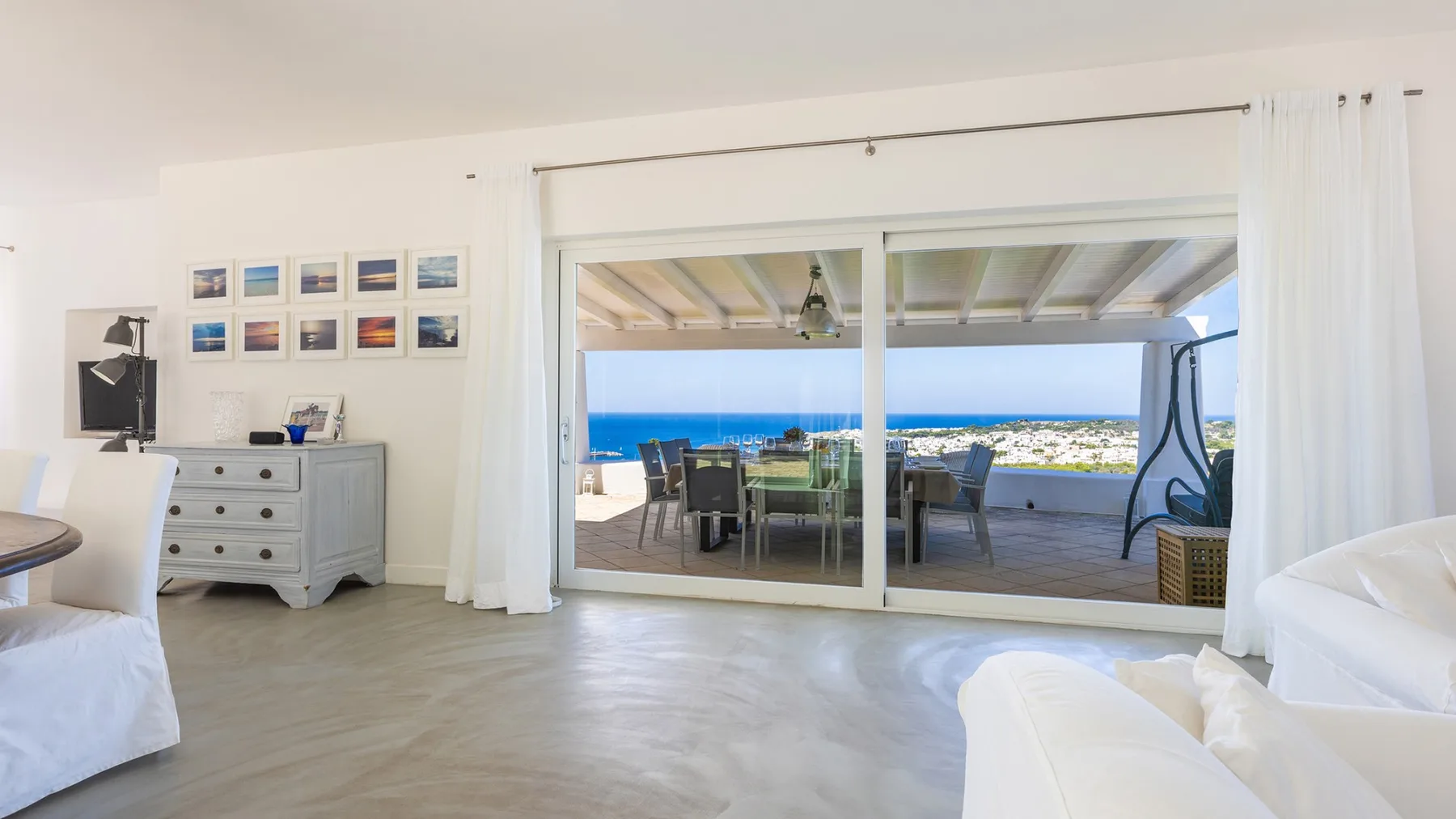 Un dormitorio luminoso se abre por puertas correderas de cristal a una terraza cubierta con vistas al mar.