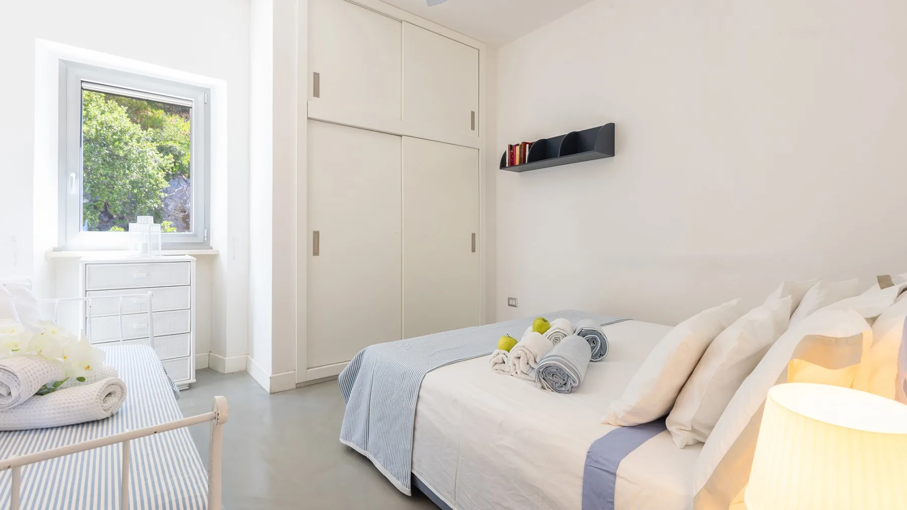 Un dormitorio luminoso con una cama, una ventana y armarios empotrados.