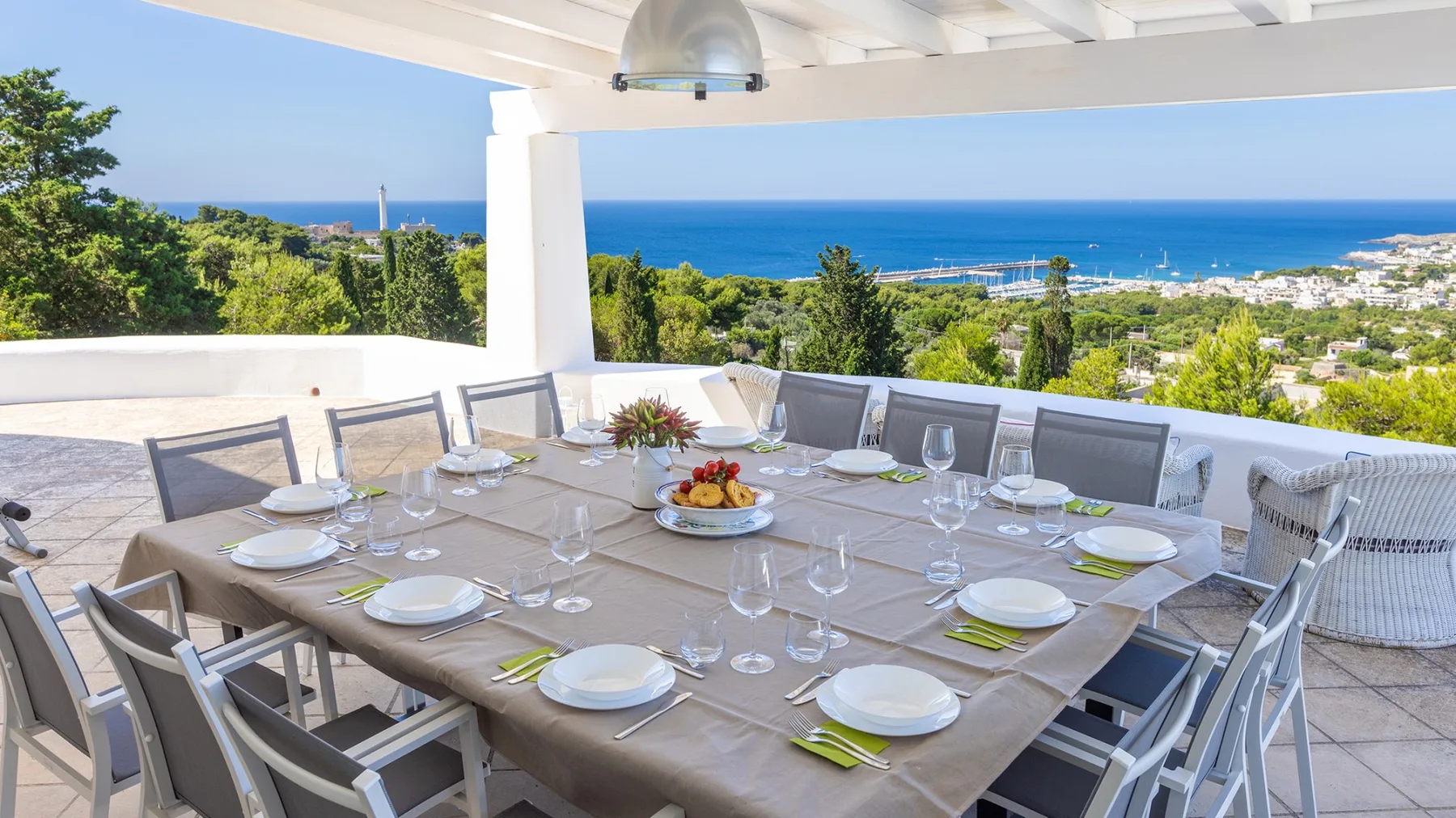 Comedor exterior cubierto con la mesa puesta y vistas al mar.