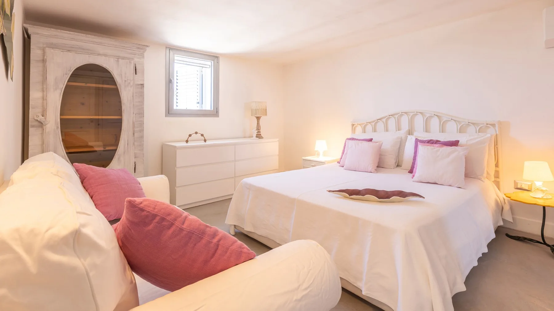 Un dormitorio luminoso con una cama tendida y una zona de descanso.