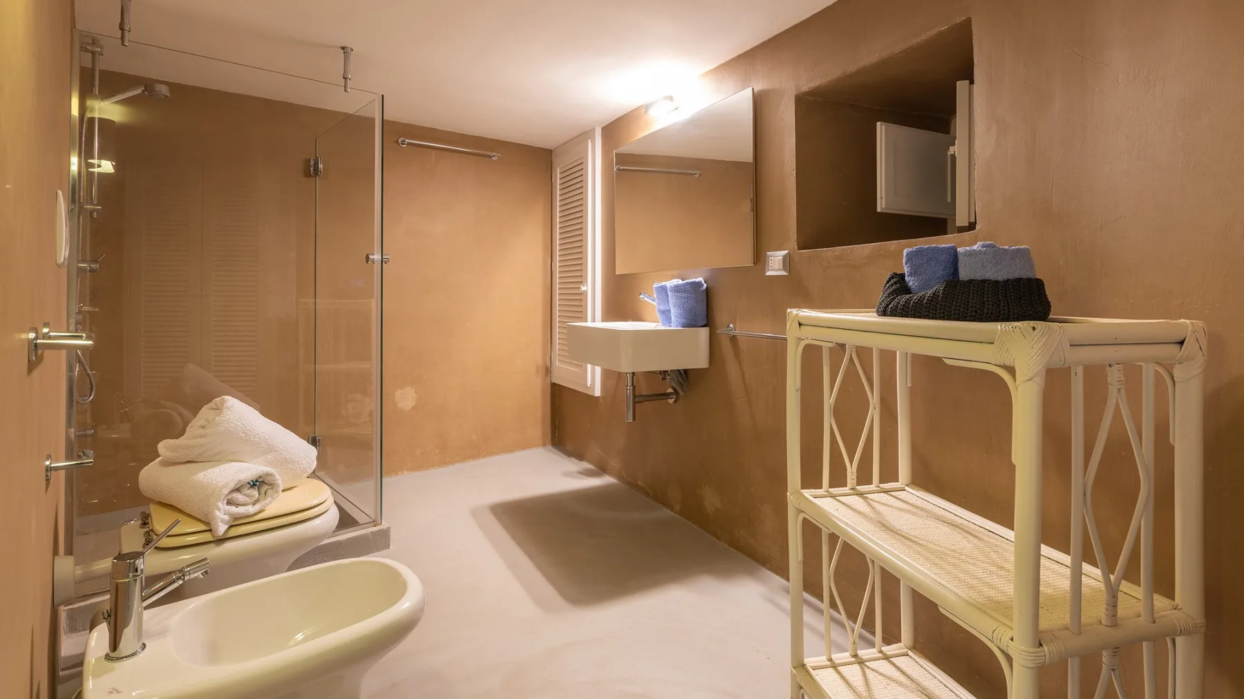 Un baño con ducha de cristal, lavabo y estanterías.