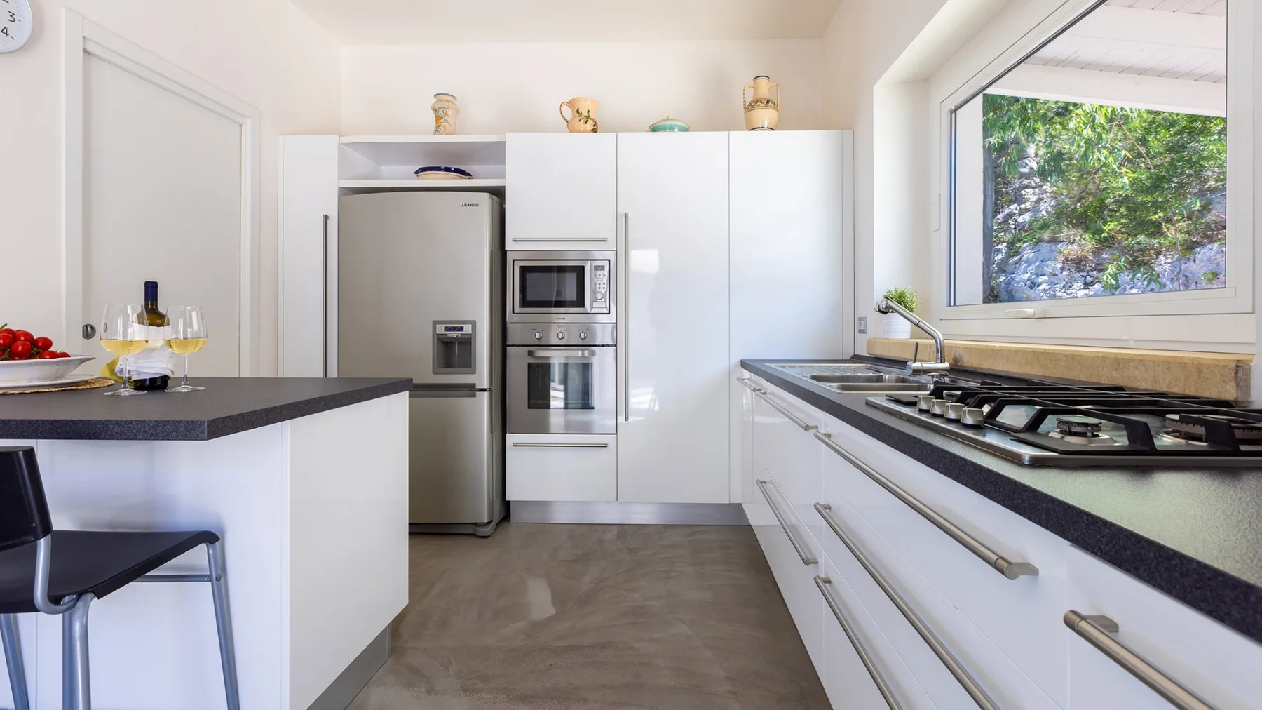 Una cocina moderna con gabinetes blancos, electrodomésticos de acero inoxidable y una encimera oscura.