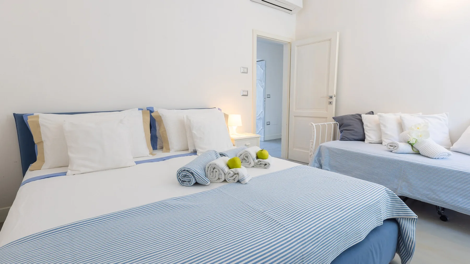 Un dormitorio luminoso con una cama grande y otra más pequeña al lado.