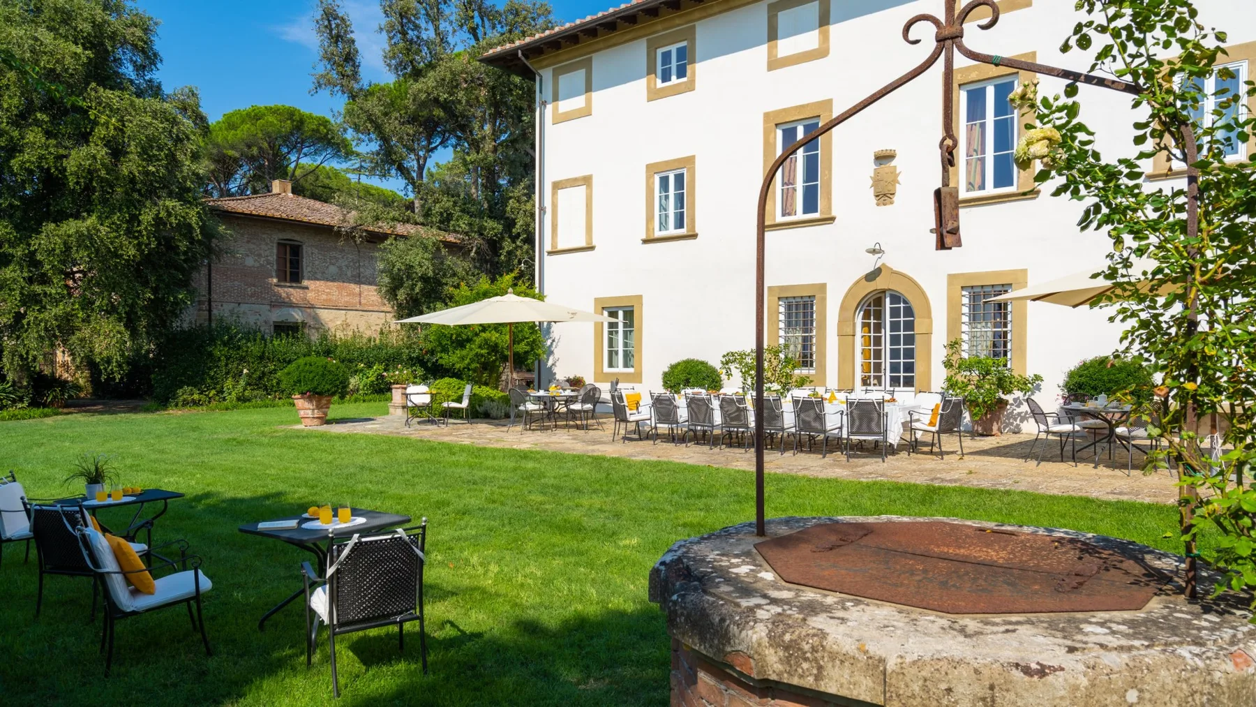 A landscaped garden with outdoor seating and a large white building.