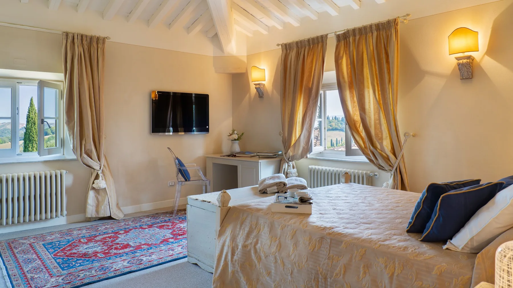 A bedroom with a bed, patterned rug, and windows beneath a sloped ceiling.