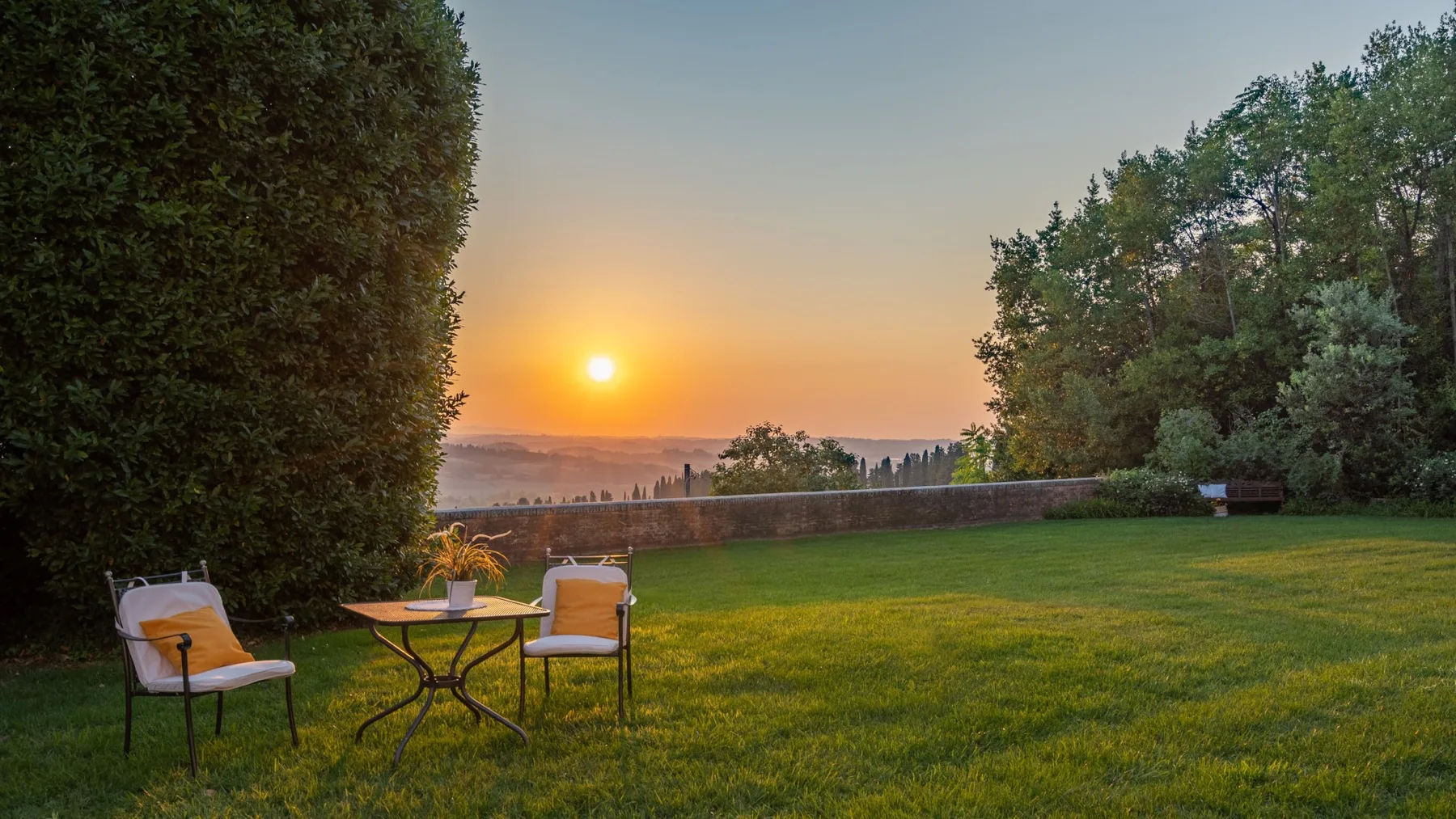 A grassy garden at sunset, with outdoor seating overlooking the distant landscape.