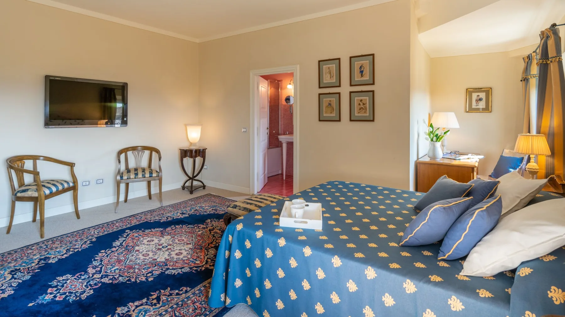 A bedroom with a blue patterned bedspread and a wall-mounted television.