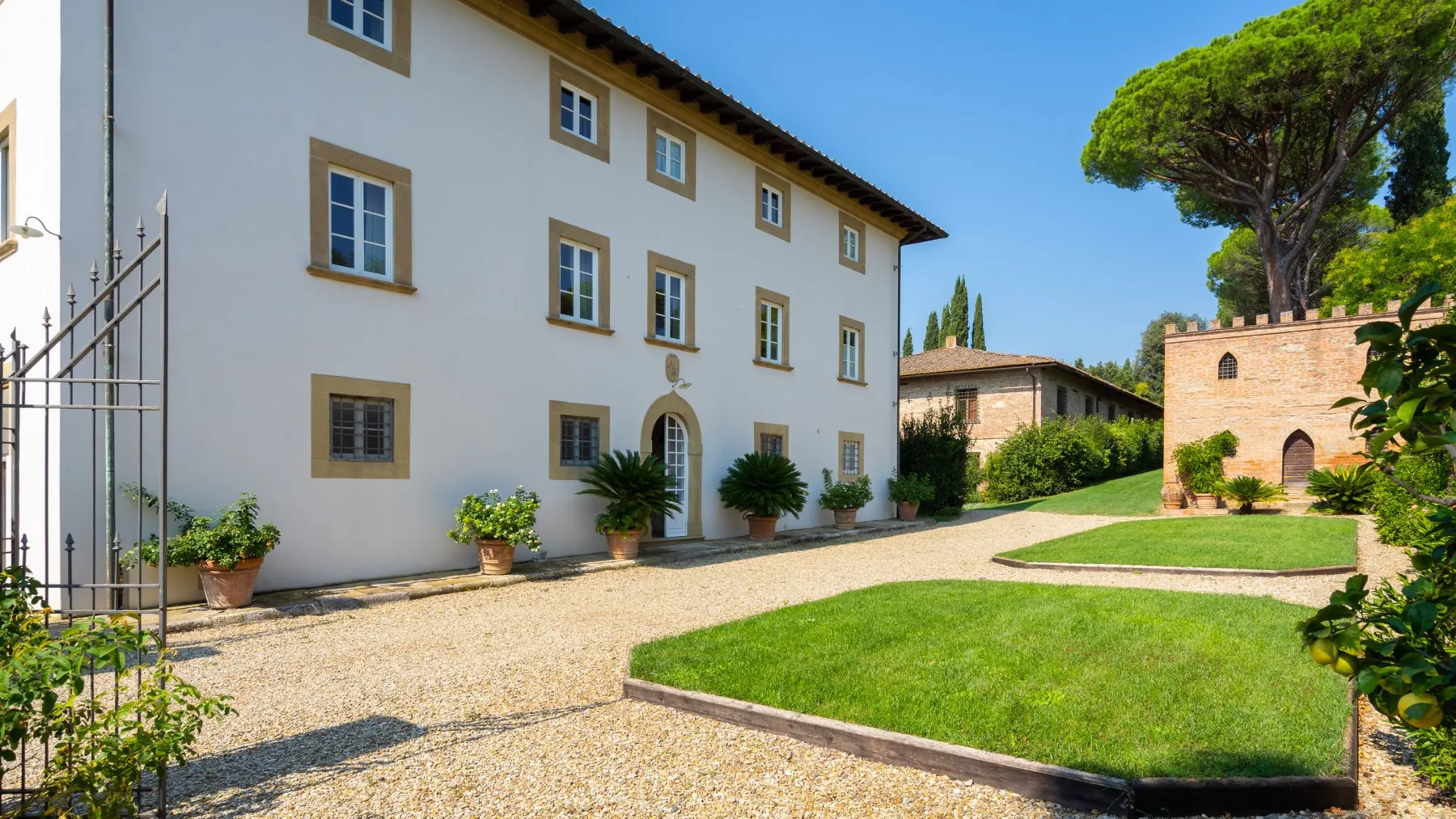 A courtyard garden with a gravel path beside a pale building.