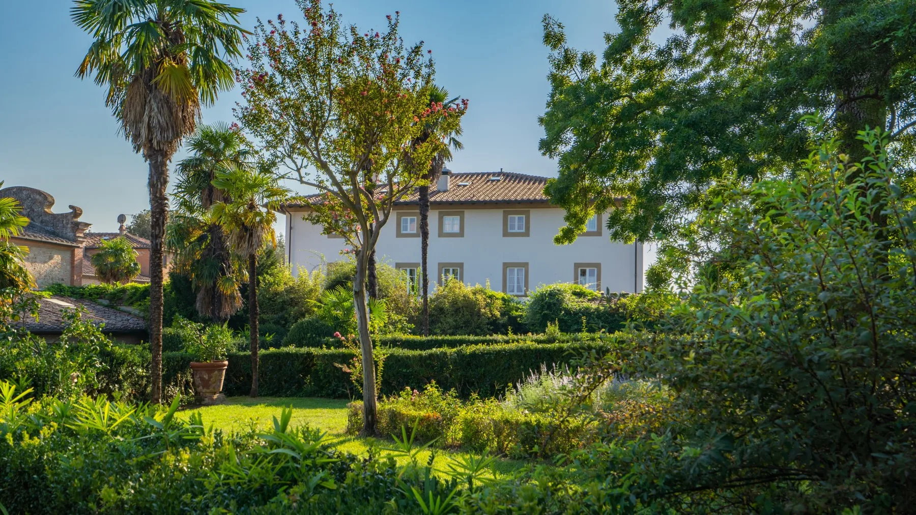 A landscaped garden with trees and shrubs in front of a building.