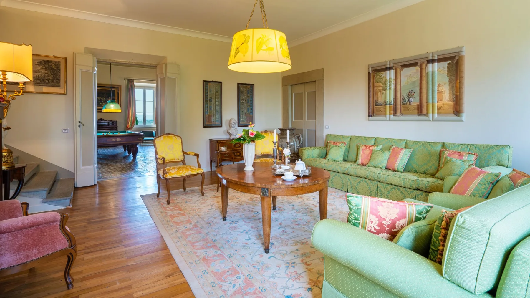 A living room with green seating arranged around a wooden coffee table.