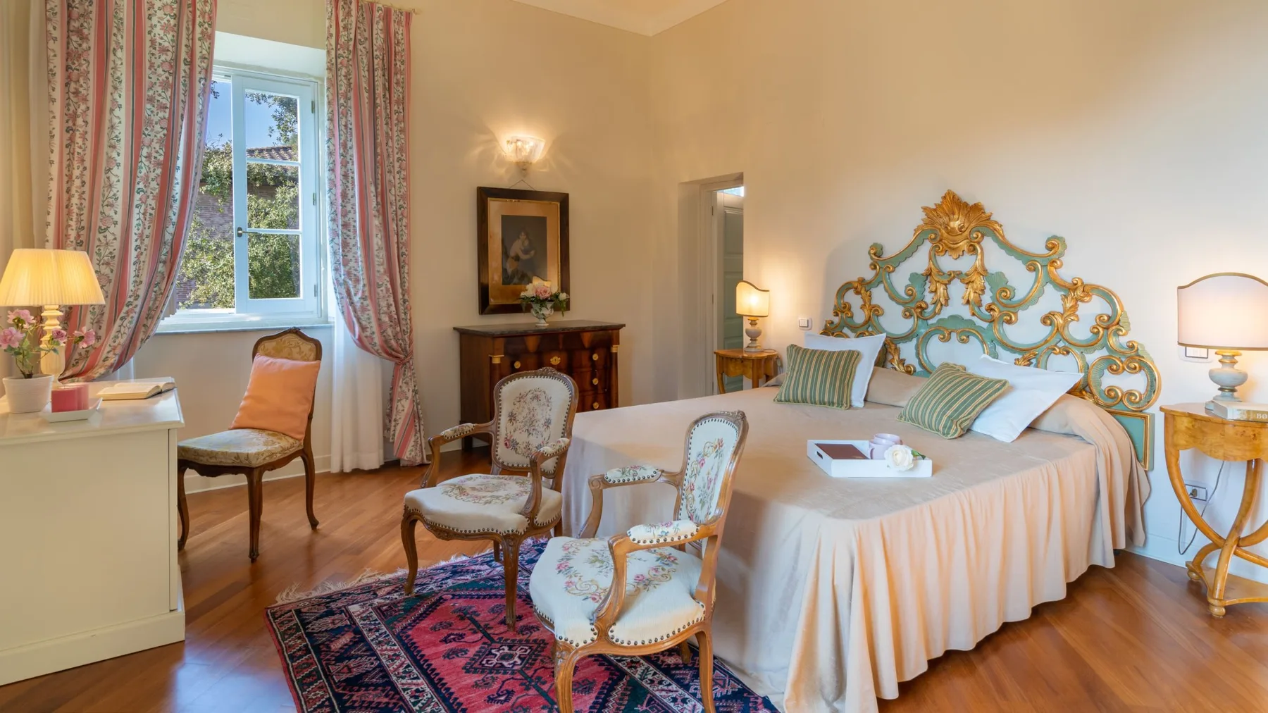 A bedroom with a large bed, patterned curtains, and wooden flooring.