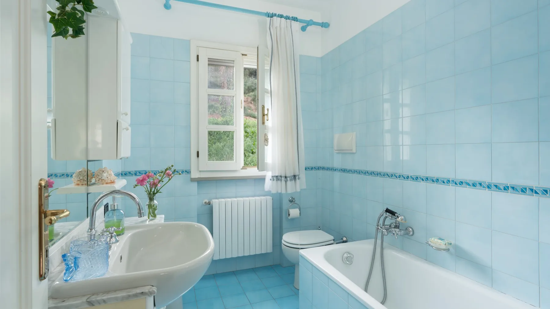 A tiled bathroom with a bathtub, sink, and window.