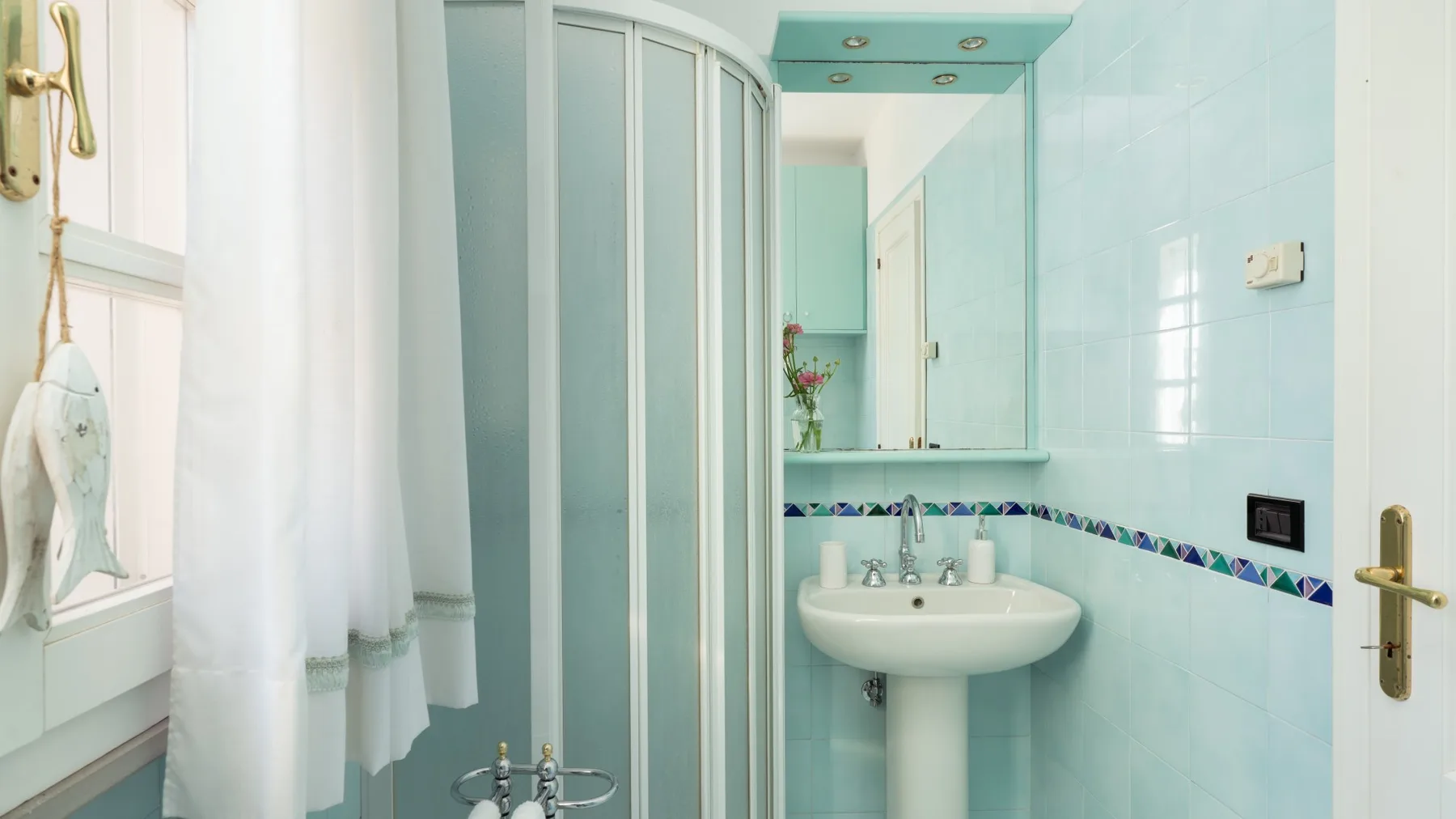A bathroom with a sink, mirror, and shower.