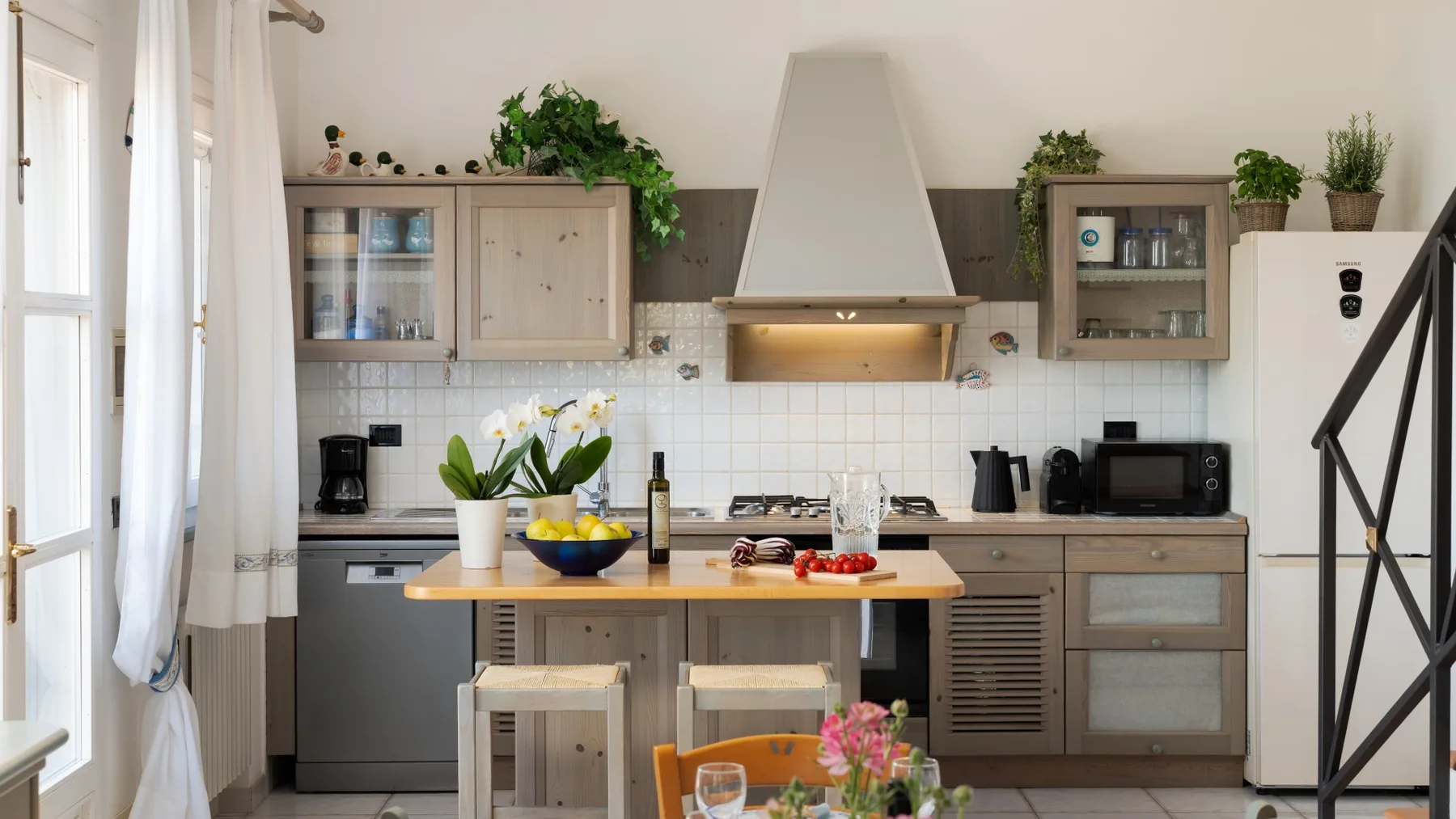 A bright kitchen with cabinets, a central island, and potted plants.